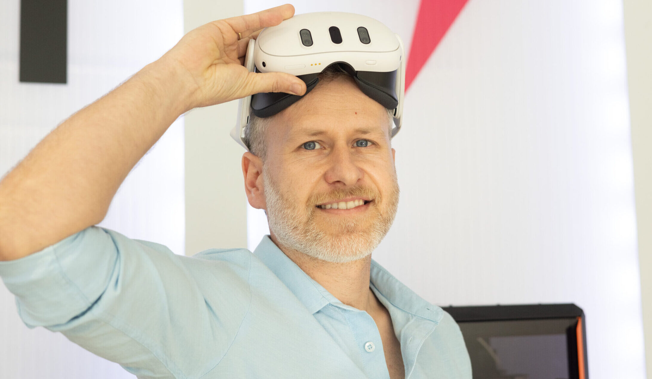 Porträtaufnahme von Georg Pöltl mit einer VR-Brille auf der Stirn, lächelnd.